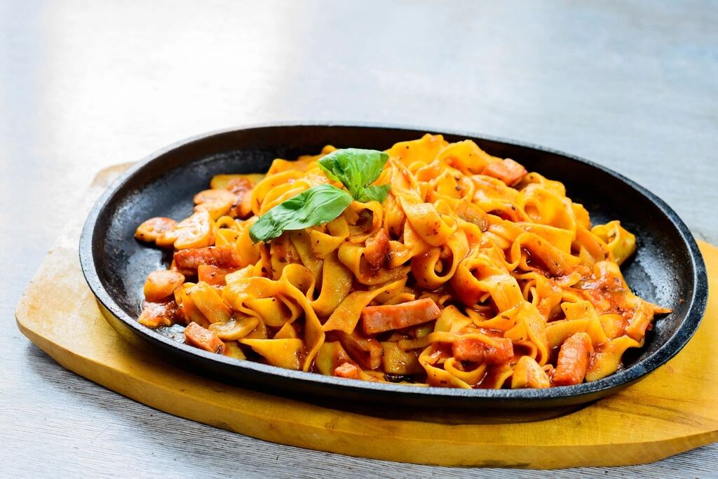 Ribbons of pasta in a rich sauce served in a cast-iron pan